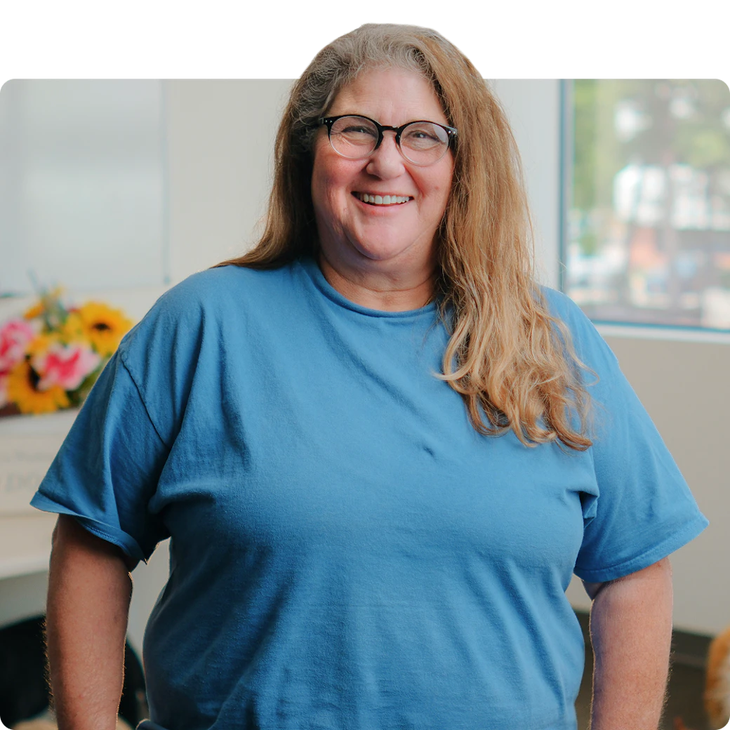 A smiling woman standing in an office, featured as Becky's PetCare customer from Springfield, VA.